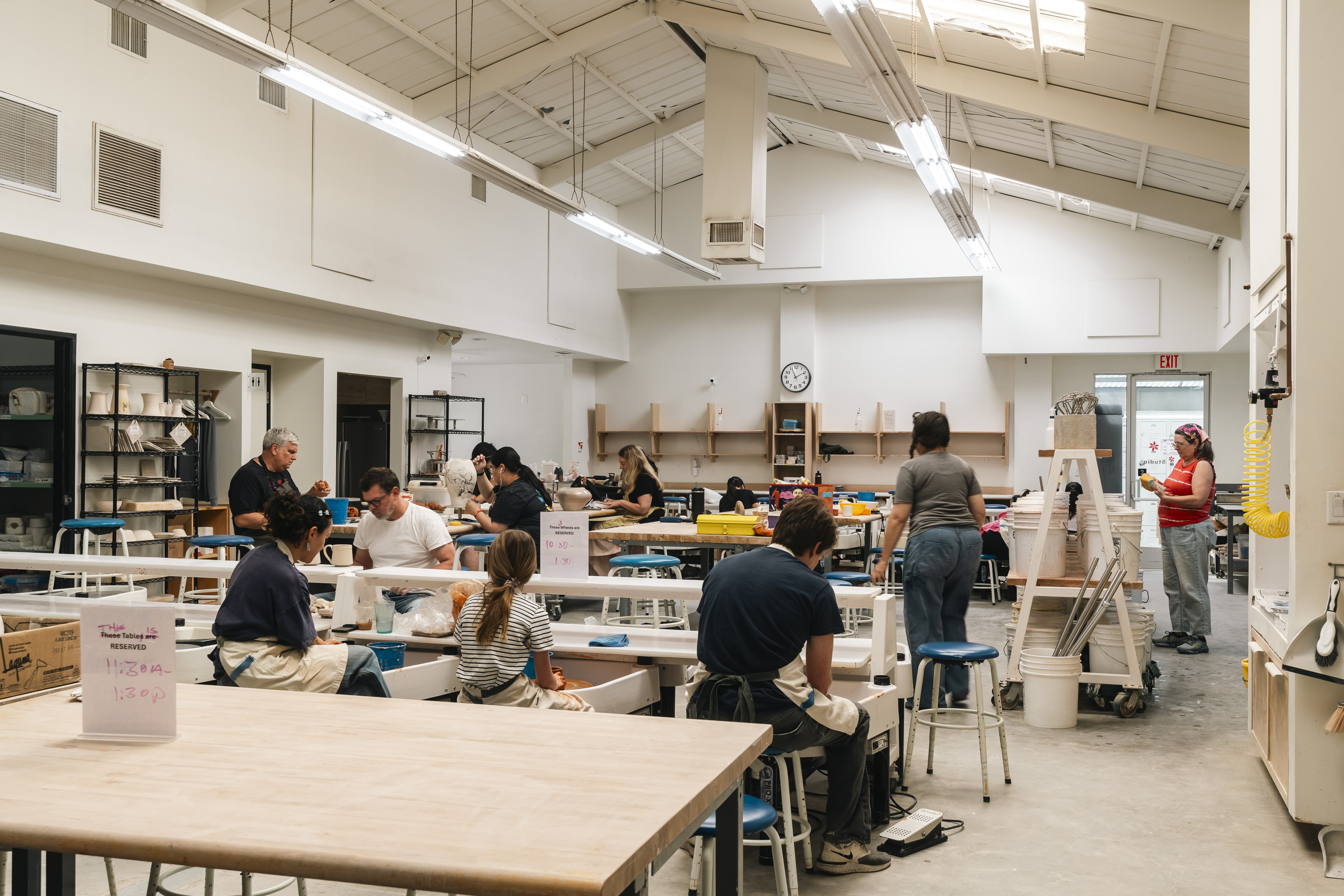 A class in session at Green & Bisque — students at wheels and tables under the skylights