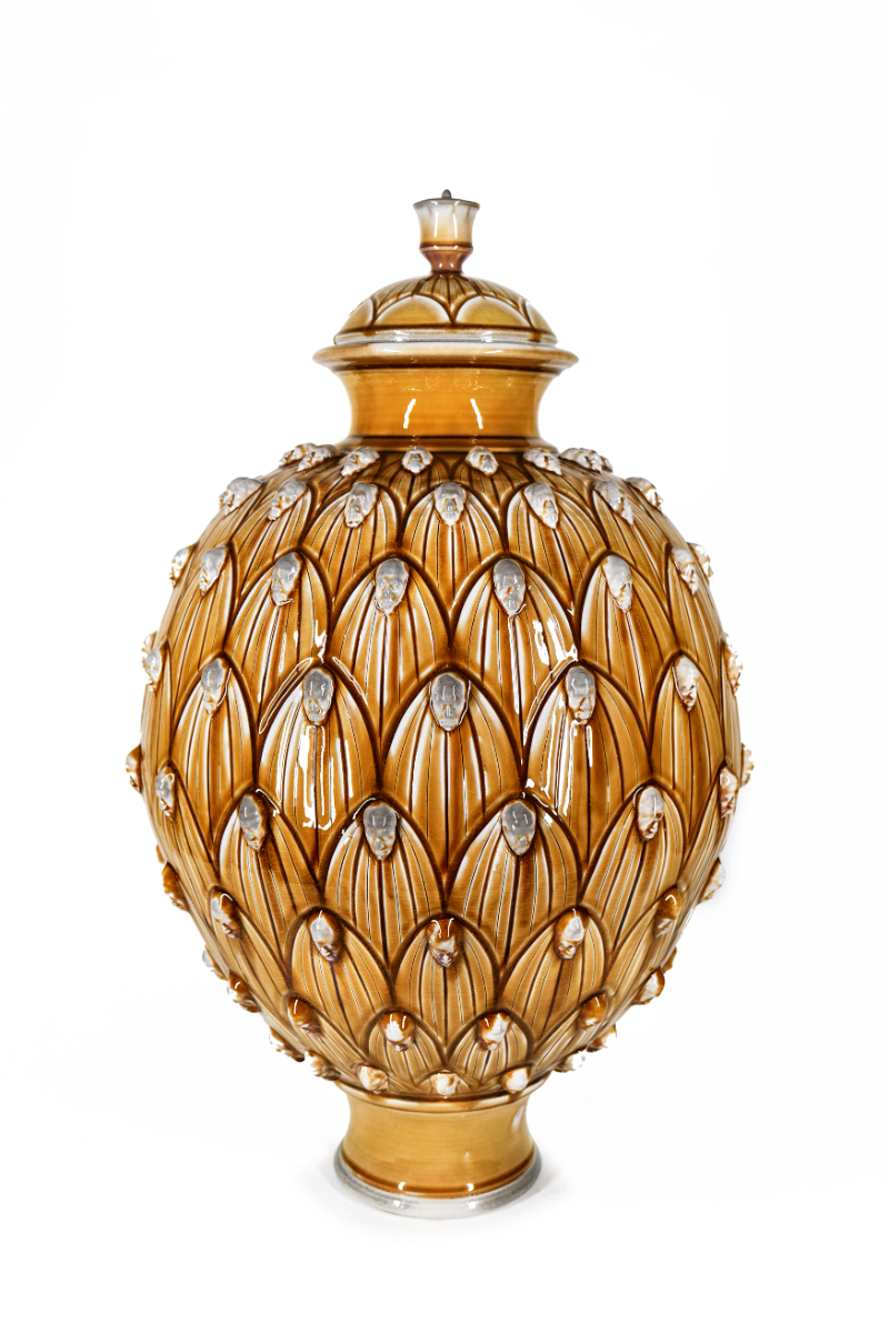 Amber-glazed lidded jar covered in carved petals with small faces