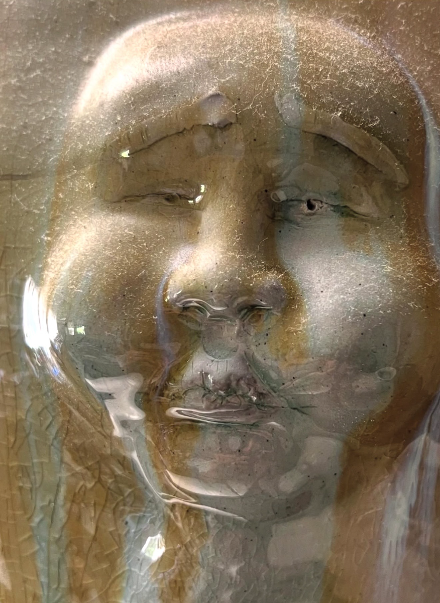 Close-up of a sculpted face under a celadon glaze