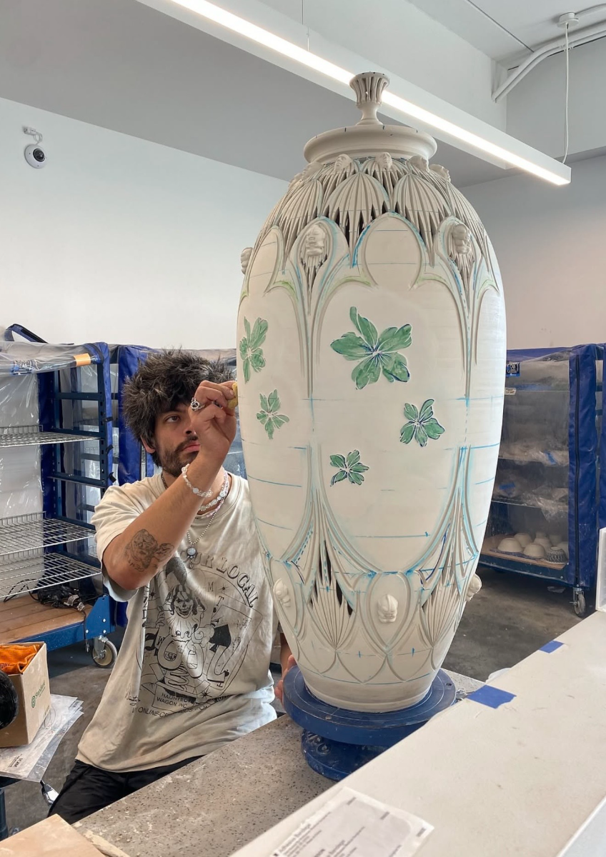 Justin Paik Reese painting green florals onto a large unfired jar