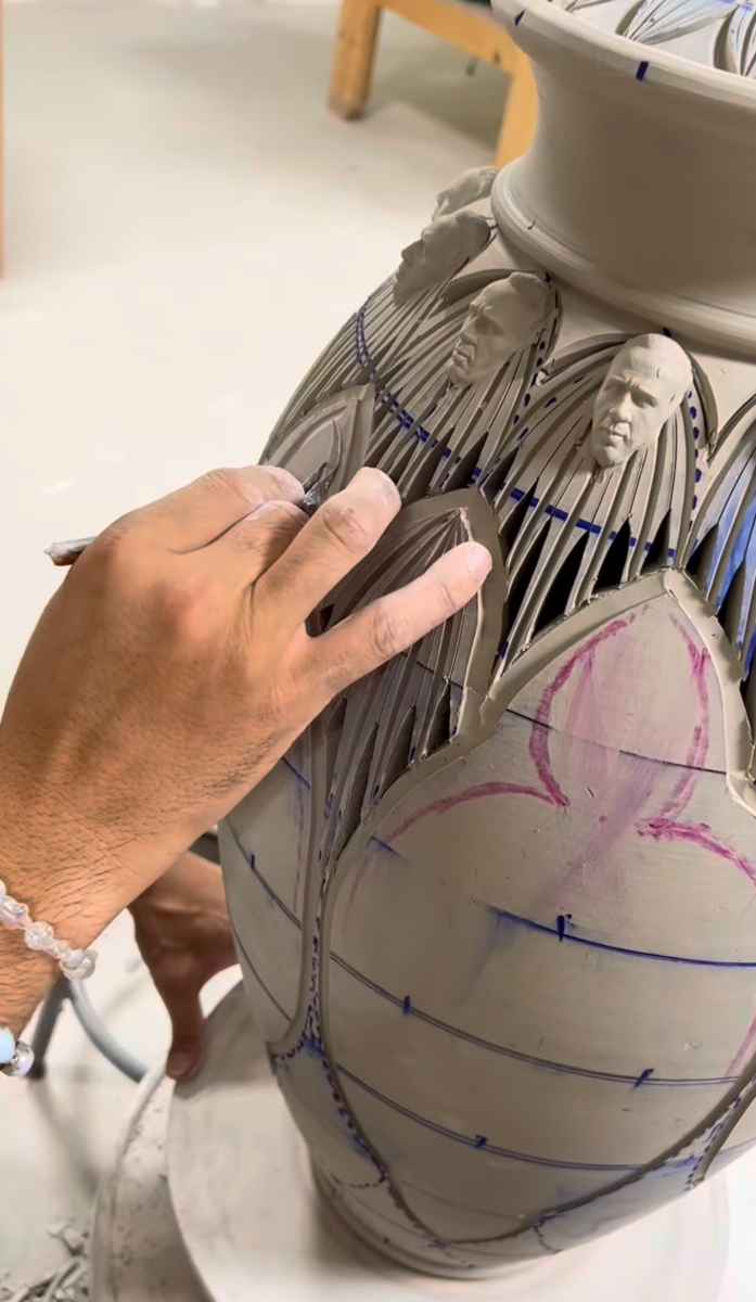 Hands carving petal forms into the surface of a leather-hard jar