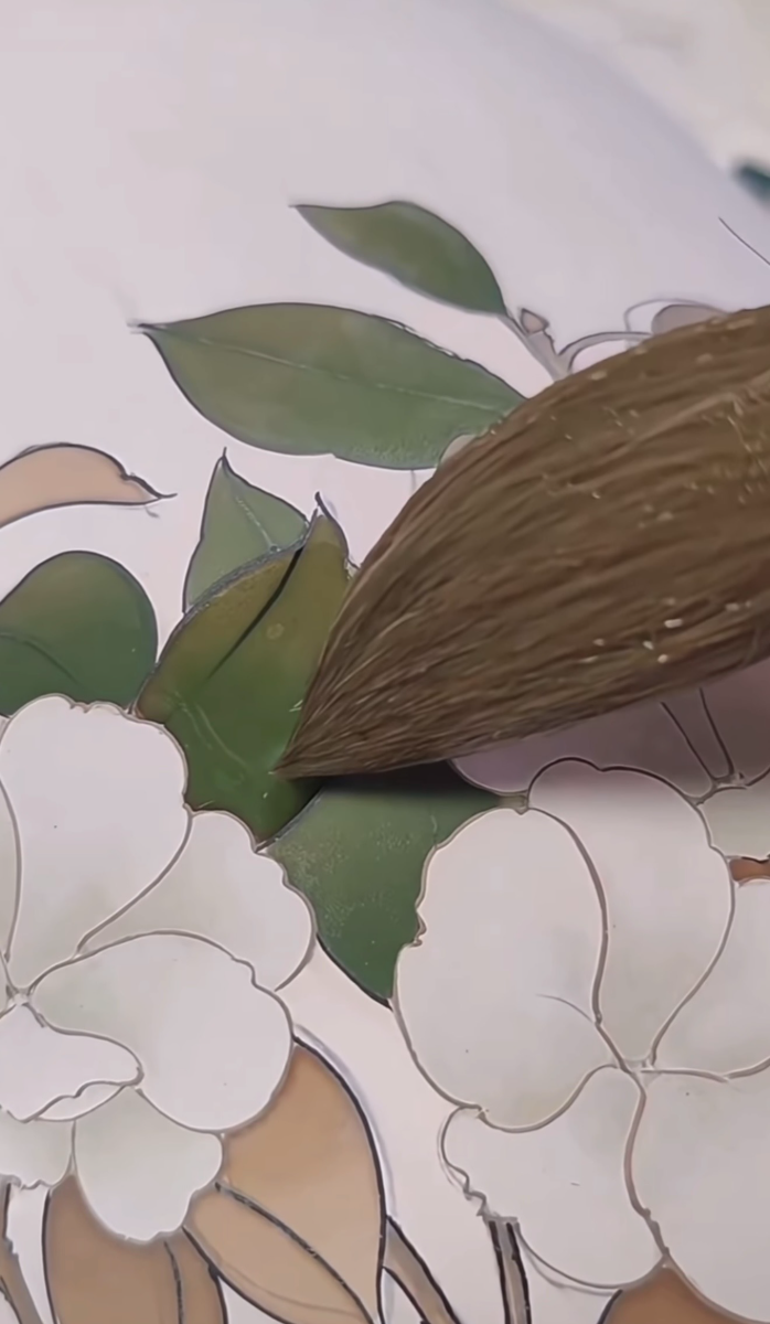Green leaves filled in around white blossoms on glazed porcelain