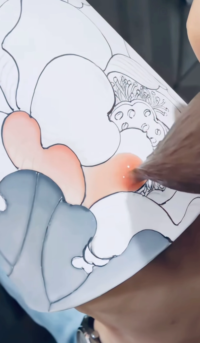 Coral and grey overglaze being applied to an outlined floral design