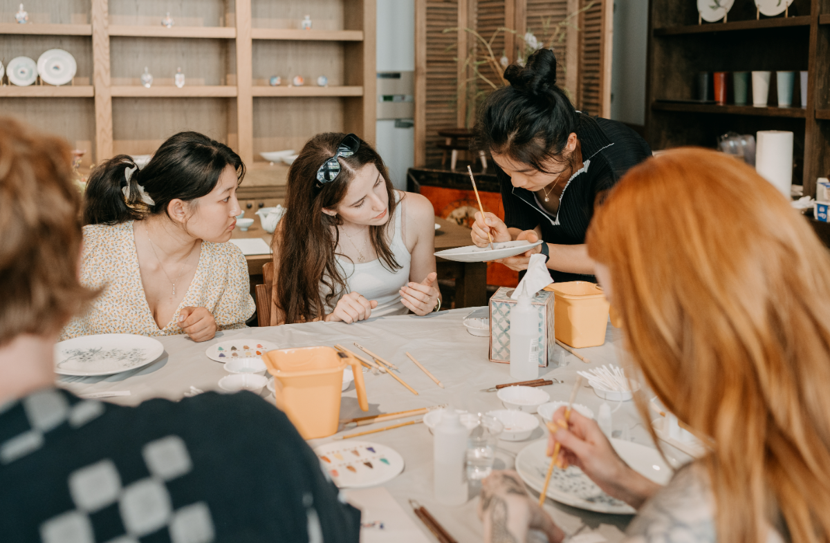 Yunting Li demonstrating brushwork to a full table of students