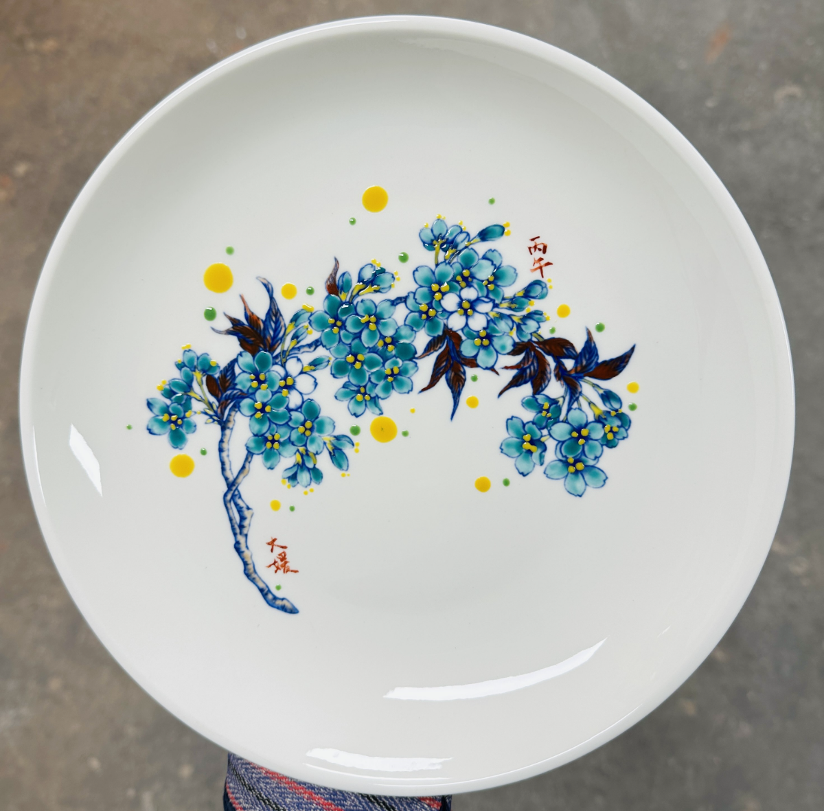 Finished plate of teal cherry blossoms with yellow accents and a red seal
